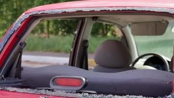 rood auto na een ongeluk met een gebroken achterzijde venster. gebroken venster in een auto met een achterzijde rem licht. interieur wrak, detailopname detail visie van een beschadigd modern auto Aan de straat. video