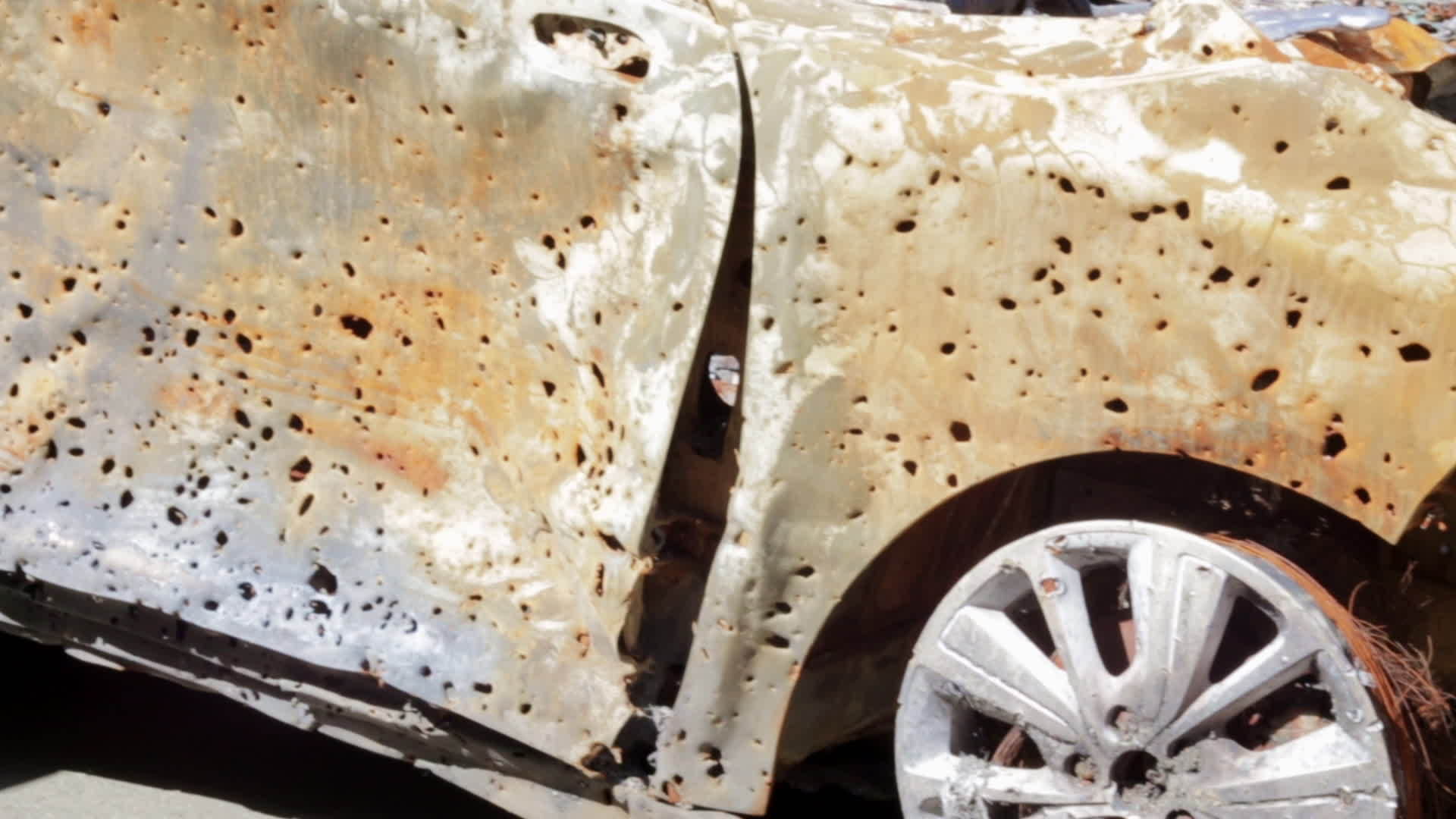 Burnt car body, riddled with bullets. War of Russia against Ukraine. Bullet holes and shell