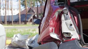 rotes Auto nach einem schrecklichen Unfall am Straßenrand. Frontal- und Seitenaufprall. Lebensversicherung. ein Unfall ohne Heilungsmöglichkeit. Rückansicht. Schäden nach einem Unfall. video