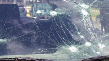 buracos de bala no para-brisa de um carro. seguro automóvel. um carro de civis, com o para-brisa quebrado, danificado pelo bombardeio. vítimas da invasão russa em grande escala do território da ucrânia. video