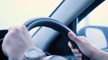 Close up of young man's hands on vehicle steering wheel as he is driving. male driving a car in the highway, hands move on the wheel in slow motion. Cars pass by in out of focus background video
