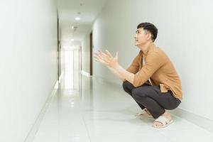 Depressed and sad woman sitting on the floor in a corridor. Low key. photo