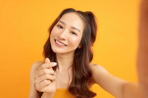 Image of excited happy young woman isolated over yellow background make selfie by camera. photo