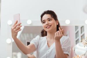 Woman makes selfie in makeup mirror with lamps photo