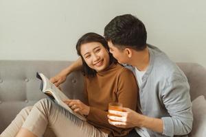 leisure, hygge and people concept - happy couple reading book at home photo