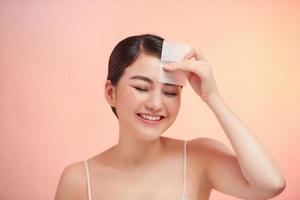 Woman Removing Oil From Face Using Blotting Papers. photo