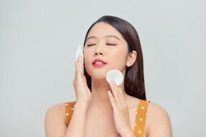 Beautiful woman cleaning face by cotton pad photo