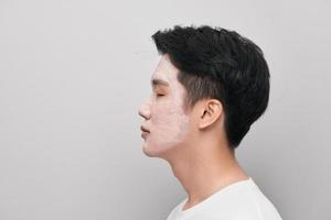 Handsome man with clay mask on his face against color background photo