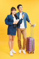 Portrait of a young beautiful couple with suitcase and looking up. Travel concept. Isolated yellow background. photo