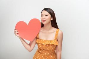 retrato de una atractiva mujer sonriente sosteniendo un corazón rojo en un fondo blanco foto