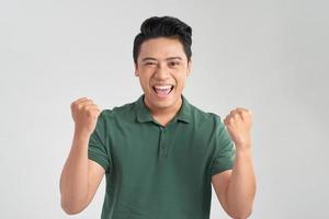 Portrait of a cheerful young man in green t-shirt celebrating success isolated over white background photo