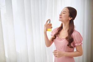 Portrait of young Asian woman applying perfume behind the window. photo