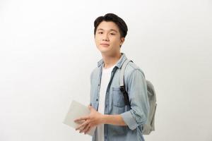 retrato de un joven estudiante universitario sonriente con libros y mochila con fondo blanco foto