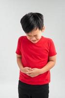Young little boy with hand on stomach because indigestion, painful illness feeling unwell. Ache concept. photo