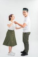 feliz pareja joven con camisetas blancas bailando y sonriendo a la cámara aislada en blanco foto