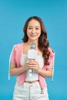 Beautiful asian woman sing a song to microphone, portrait studio on blue background. photo