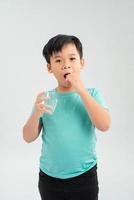 Young little Asian boy taking tablet medicine with a glass of water. Healthcare and Medical concept. photo