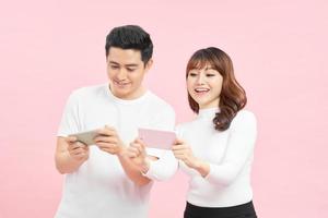 concepto de tecnología y personas - pareja feliz en camisetas blancas con smartphones sobre fondo rosa foto
