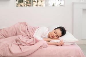 feliz mujer asiática joven belleza durmiendo y sonriendo en la cama por la mañana foto