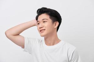 Young handsome man wearing white t-shirt over isolated background Smiling confident touching hair with hand up gesture photo