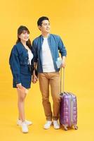 Traveler asian couple with backpack and suitcase standing isolated over yellow background. Couple Asian going to summer vacation. People, active lifestyle, relaxation and joy concept. Happy couple. photo