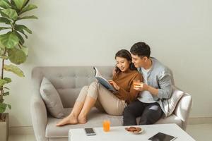 Attractive couple reading book on the sofa at home in living room photo