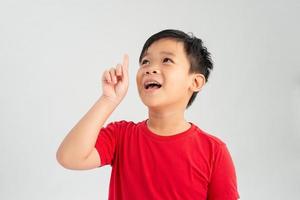 Cheerful little boy pointing up over white background photo