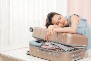 Woman prepare travel suitcase at home. Excited woman trying to close full suitcase. photo