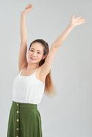Happy young Asian woman hands up in the air over white background. photo