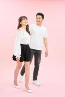 full length portrait of happy couple in casual outfit walking forward together on pink background photo