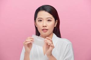 Young asian skin care woman smile and use oil blotting paper on her face photo