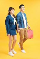 Beautiful young couple with shopping bags. Isolated on yellow background photo