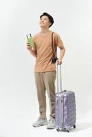 Young man with suitcase, camera and ticket on white background photo