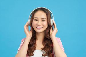 Happy Asian teenage girl listen the music song in wireless headphone from mp3 player technology. relaxation and music lover concept. photo