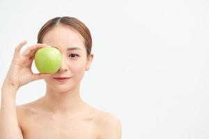 primer plano mujer medio desnuda 20 años piel perfecta maquillaje desnudo mantenga manzana aislada sobre fondo blanco retrato de estudio. foto