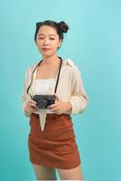 Portrait smiling girl in summer clothes with camera and backpack behind on blue background. Travel and tourism. Copyspace photo