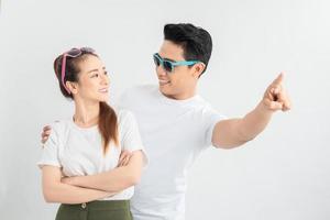 happy asian man hugging smiling girlfriend while pointing with finger isolated on white photo