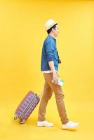 feliz turista masculino con bolsa de viaje y cámara lista para el viaje, aislado en amarillo foto