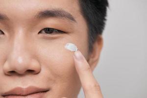 Young handsome man using cream isolated on white photo