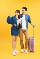 young travelling couple with suitcases pointing somewhere isolated on yellow photo