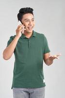 Cheerful casual man talking on phone and celebrating standing on white studio background photo
