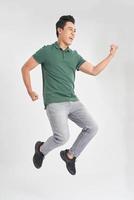 Full-length photo of funny man 30s in casual t-shirt and jeans running or jumping in air isolated over white background