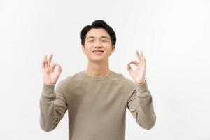 Portrait of happy young asian man dress in casual informal smiling and posing with cheerful and okey hand sign photo