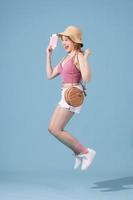 Young overjoyed asian woman in summer clothes dress straw hat jump up isolated on pastel blue background photo