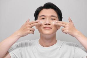 Young man with moisturizer on the face photo