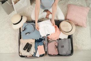 Passport in girl hand and travel accessories costumes, luggage, camera, clothes in suitcase, prepared for the trip and travel concept photo