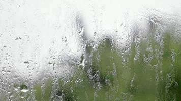 chuva pesada. gotas de chuva no vidro da janela em um dia de verão. foco seletivo, profundidade de campo rasa. gotas de água caem em uma janela molhada. copo cheio de gotas durante uma chuva. panorama. video