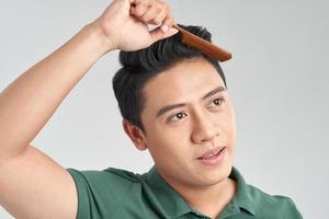 Smiling man in green t-shirt combs his hair photo