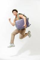 Young excited Asian tourist man with baggage jumping in mid-air ready to travel isolated photo