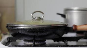 A frying pan on a home gas stove with a glass lid. Steam is coming. Cooking. A frying pan on fire on a gas stove burner. Energy crisis and rising energy prices. video